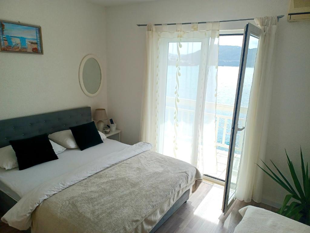 a bedroom with a bed and a large window at Apartmani Leženić Dada in Neum