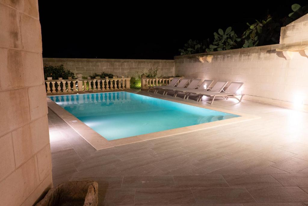 a swimming pool at night with chairs around it at Surwig Gozitan Villa & Pool - Happy Rentals in Kerċem