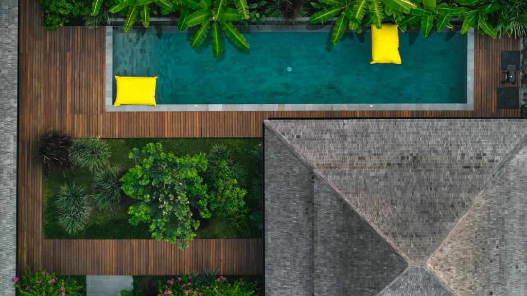 an overhead view of a swimming pool with yellow chairs at July Villas in Canggu