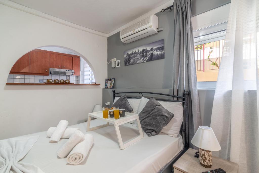 een kleine slaapkamer met een wit bed en een tafel bij Oasis Studios in the City Centre in Heraklion