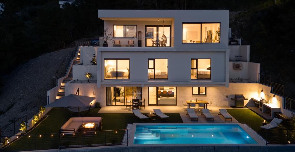 une grande maison avec une piscine en face de celle-ci dans l'établissement New! Villa Sunset Split overviewing Split and Podstrana bay, à Strožanac
