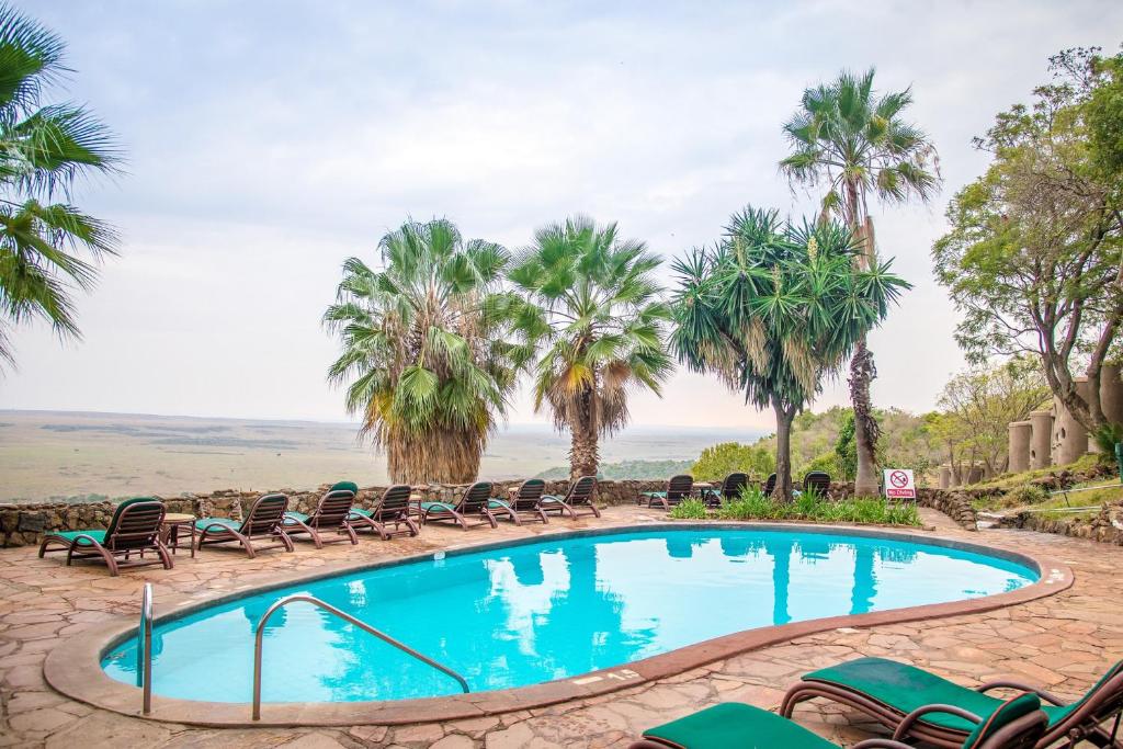 a swimming pool with chairs and palm trees at Mara Serena Safari Lodge in Lolgorien