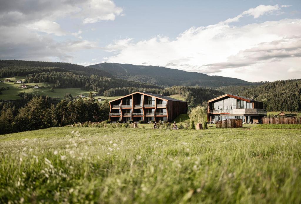 a house in a field with mountains in the background at AEON Hotel - adults only Bed & Breakfast in Soprabolzano