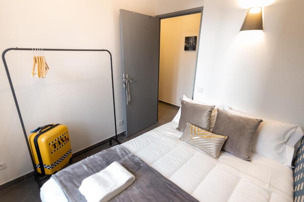 a bedroom with a white bed with pillows and a yellow suitcase at We Love Paris - Private Apartment in Vitry-sur-Seine