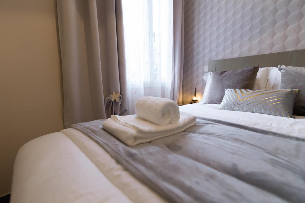 a white bed with a pile of towels on it at We Love Paris - Private Apartment in Vitry-sur-Seine