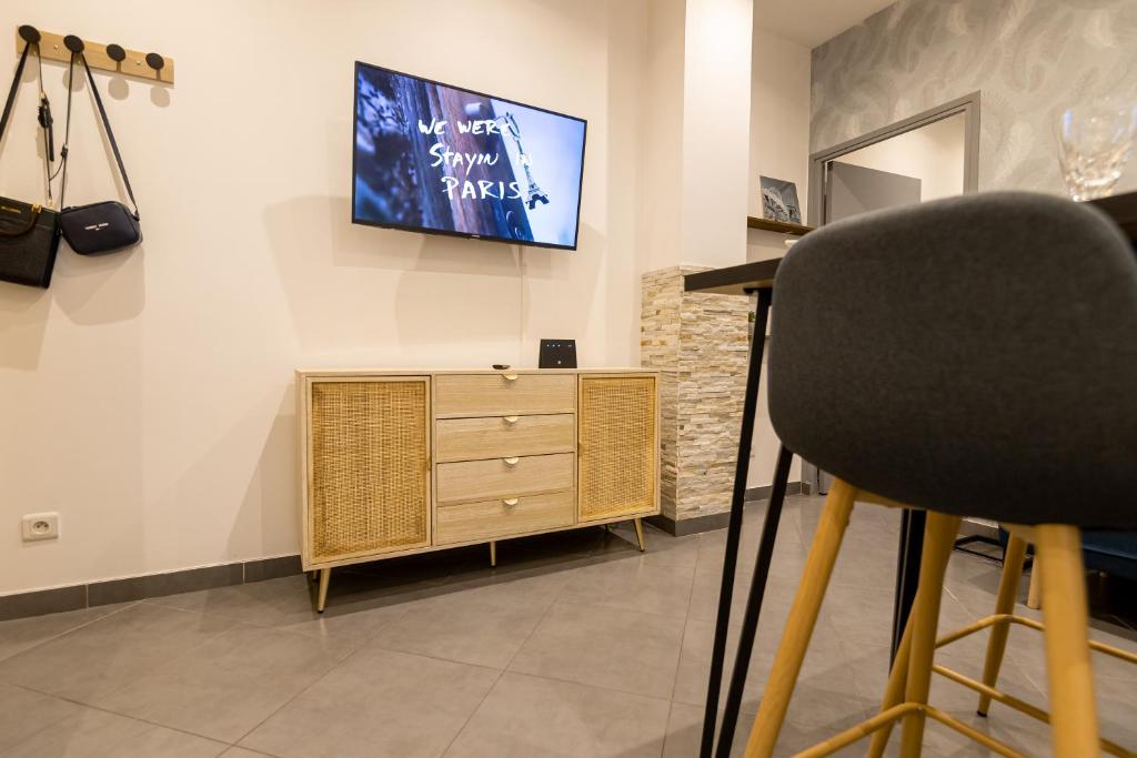 a chair in a room with a tv on a wall at We Love Paris - Private Apartment in Vitry-sur-Seine