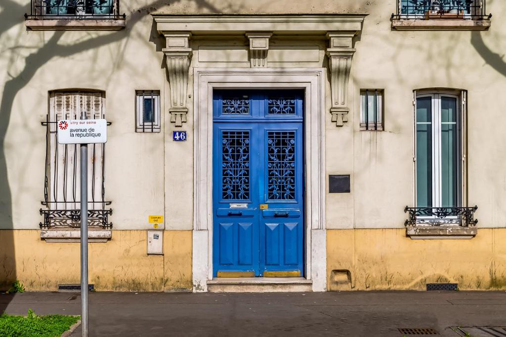 a blue door on the side of a building at We Love Paris - Private Apartment in Vitry-sur-Seine