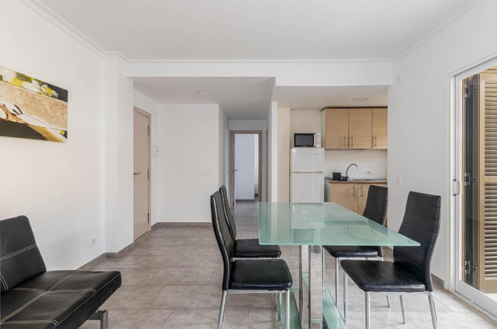 a dining room with a glass table and black chairs at Acapulco Apartments in Can Picafort