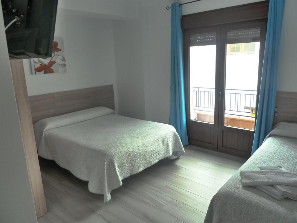a bedroom with two beds and a window with a balcony at Hostal Casa Fermina- A 2 horas de las pistas de esquí in Trevélez