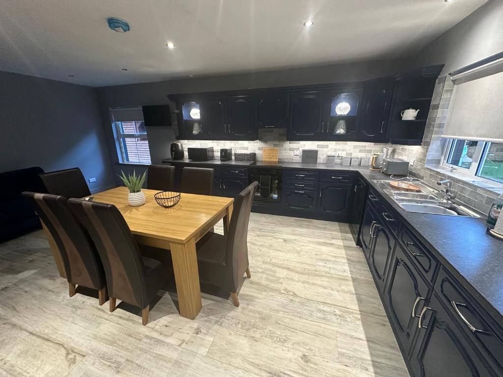 a kitchen with a wooden table and black cabinets at Mac's Cottage in Clogher