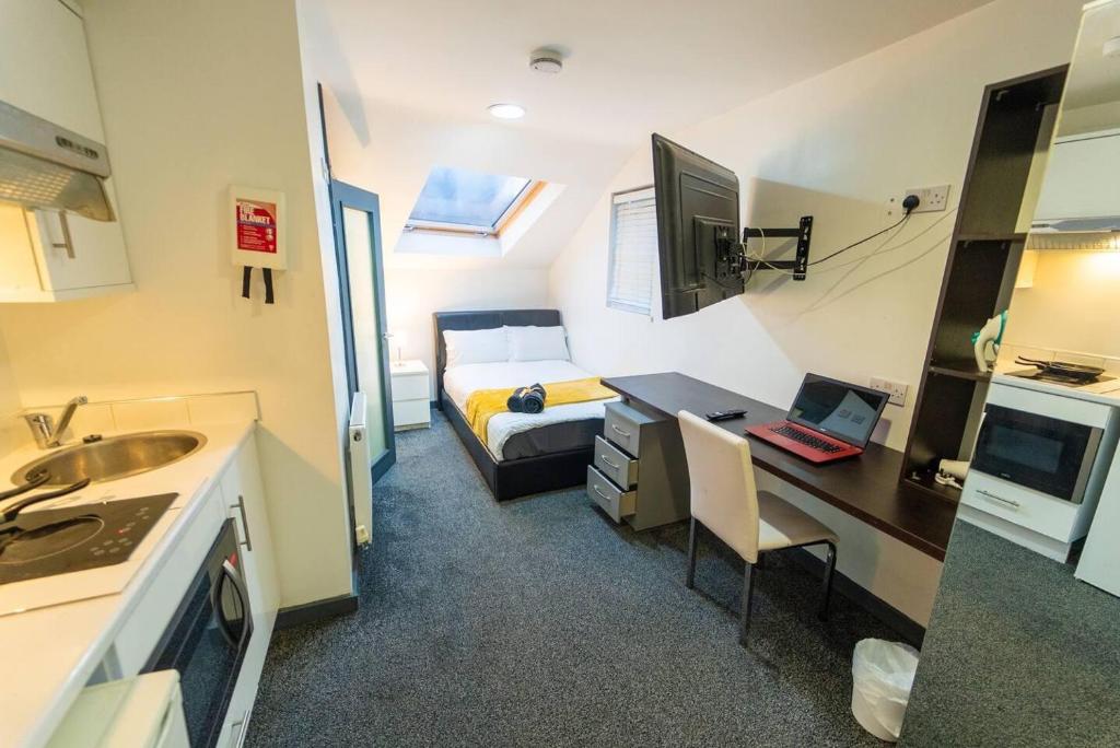 伯明翰Spacious Comfortable studio near the university的一间带一张床和一张带电脑的桌子的小房间