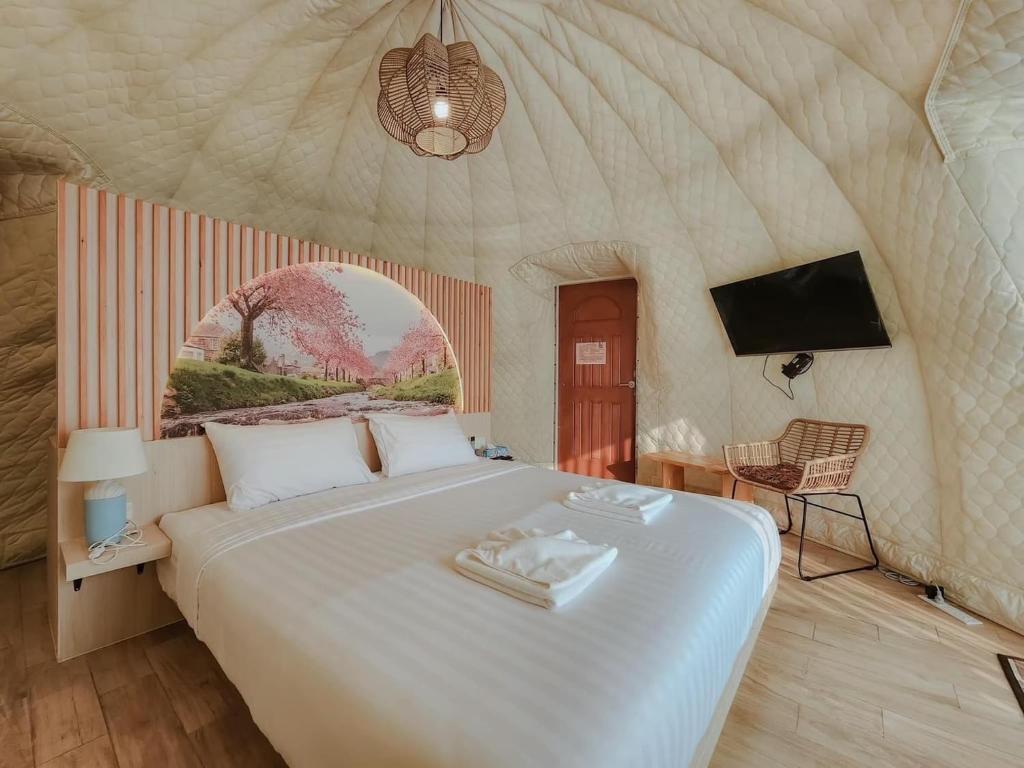 um quarto com uma grande cama branca e uma televisão em Dome The Heavenrest em Ban Khlong Ta Sang