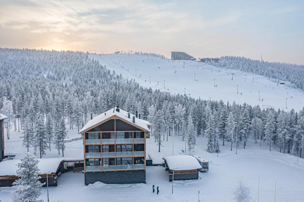 a building on a ski slope with snow covered trees at Tunturinlaita A4, Ski-in Ski-out 3xbedroom Levi in Kittilä