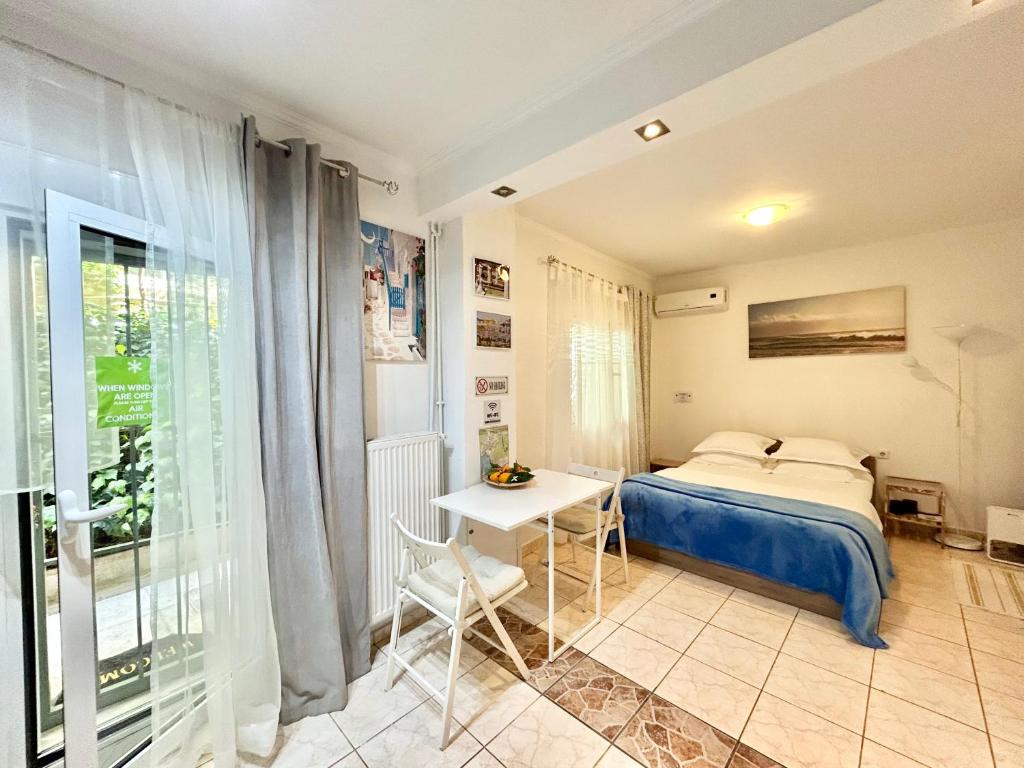 アテネにあるMon apartment Alkionis Palaio Faliroのベッドルーム1室(ベッド1台、テーブル、窓付)