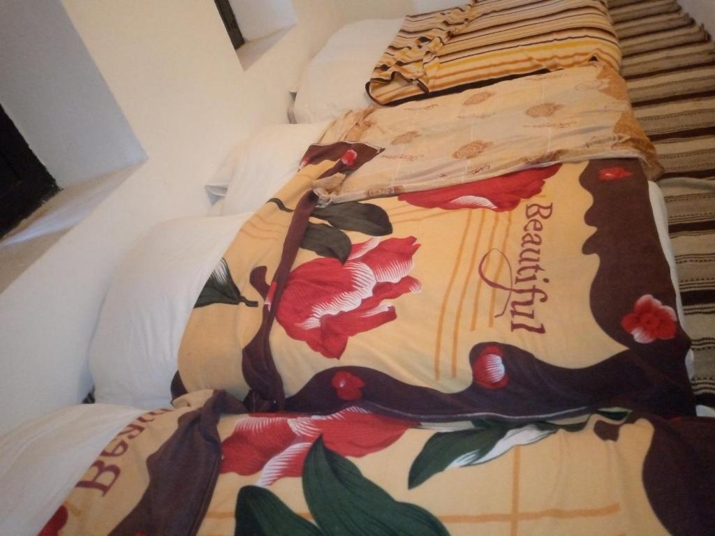 Guest house tassaoute : سرير مع لحاف عليه زهور