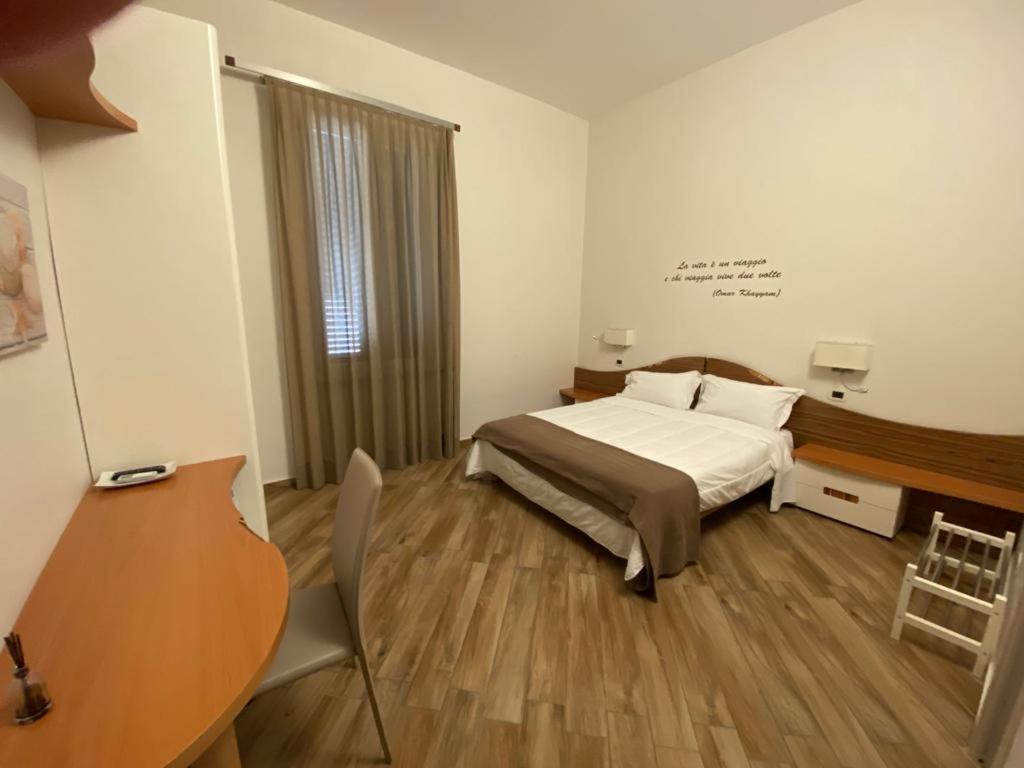 um quarto com uma cama, uma secretária e uma mesa em A 4 PASSI em Reggio di Calabria