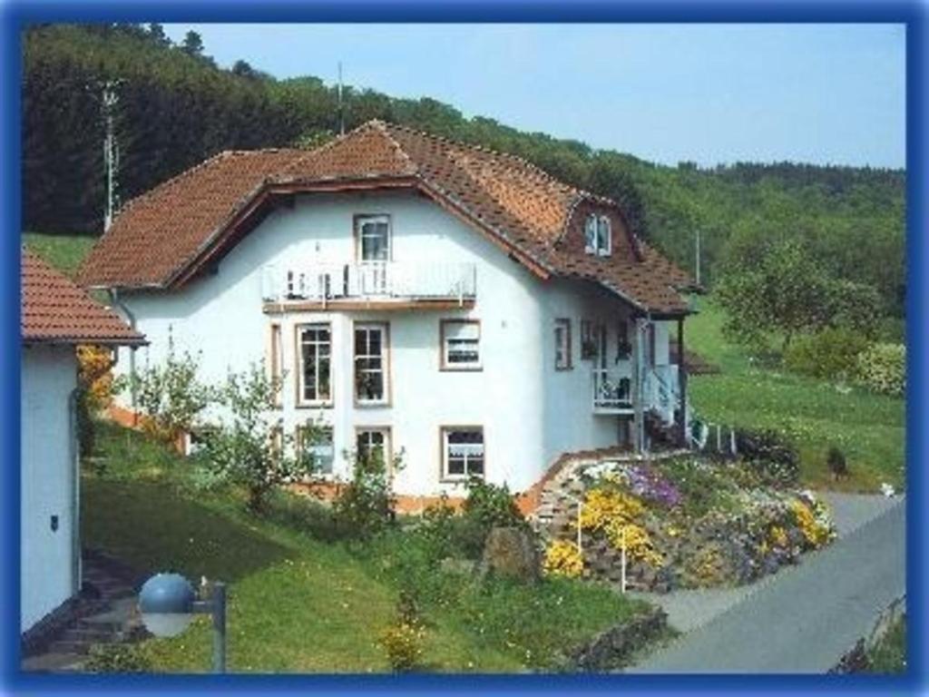una gran casa blanca sentada en la cima de una colina en Ferienwohnung für 6 Personen ca 68 qm in Daun-Weiersbach, Rheinland-Pfalz Moseleifel en Daun