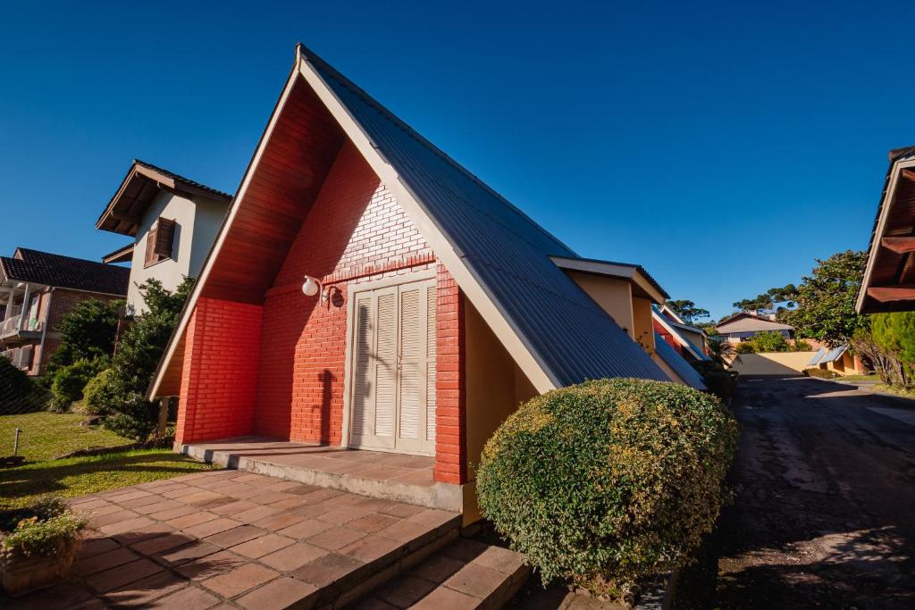 uma pequena casa de tijolos vermelhos com uma porta branca em Hotel Cabanas Alto Da Serra em Canela