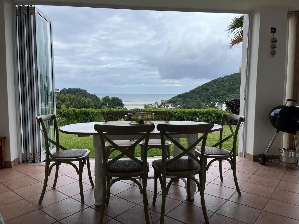 a table and chairs on a balcony with a view of the ocean at The Estuary Country Estate, Villa "Once Upon A Tide" in Port Edward