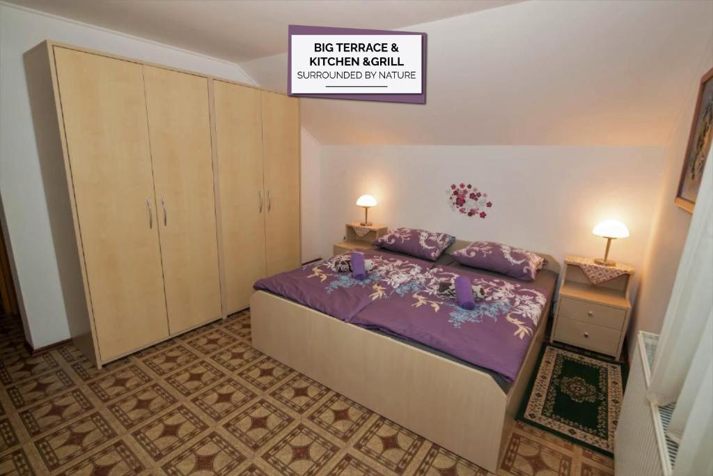 1 dormitorio con 1 cama grande con sábanas moradas en Apartments Orel, en Mozirje