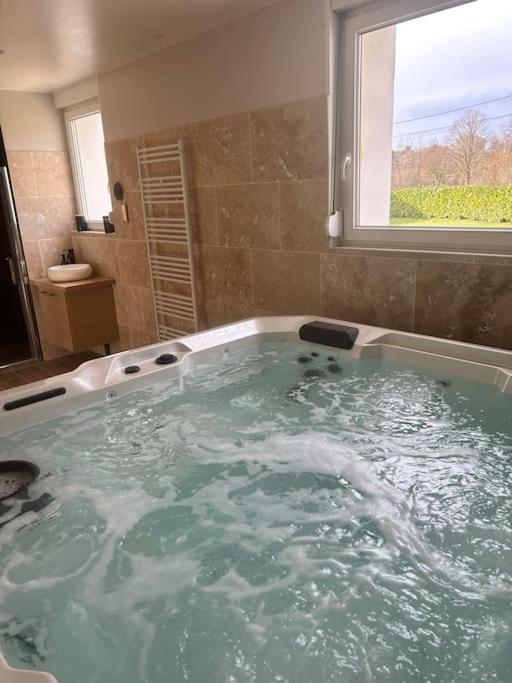La salle de bains est pourvue d'une grande baignoire et d'une fenêtre. dans l'établissement Chez Balthazar, à Elnes