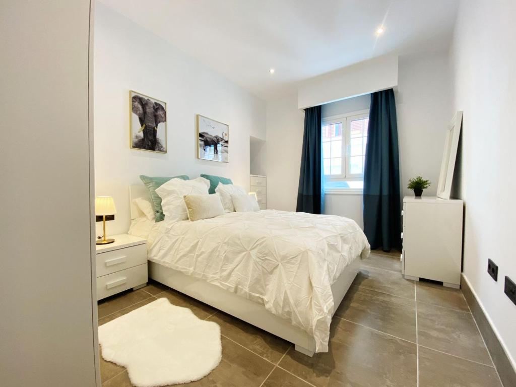 a white bedroom with a large bed and a mirror at Apartamento en C/ León y Castillo (C/ Real) Centro de Arrecife in Arrecife