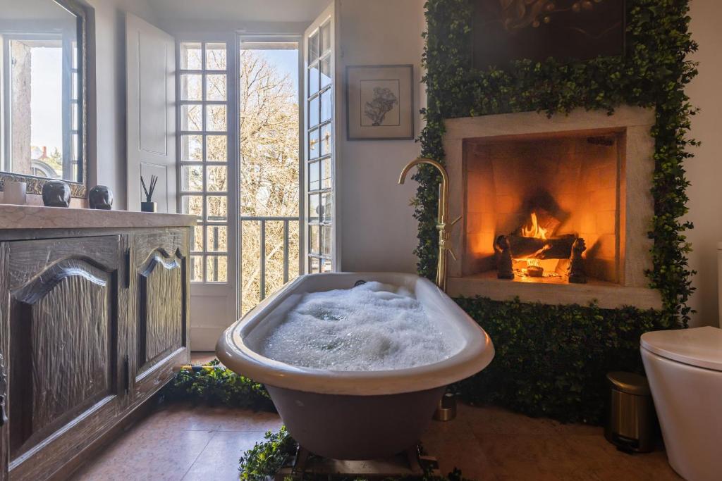 uma casa de banho com banheira em frente a uma lareira em Sintra WOW - Unique double Smart Room in 17th century Palace! Hot tub, Snooker, BBQ, PS5, Sauna, Gym em Sintra