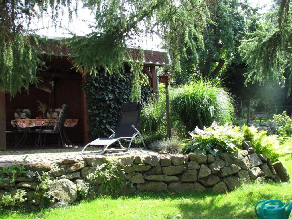 une chaise assise dans une cour à côté d'un mur en pierre dans l'établissement "Heidi" Modern retreat, à Kirschau