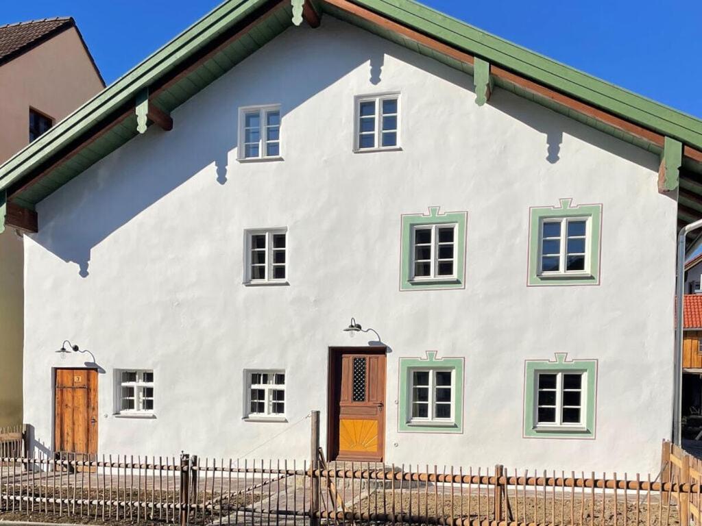 uma casa branca com janelas verdes e uma cerca em Zum Bräu Modern retreat em Polling