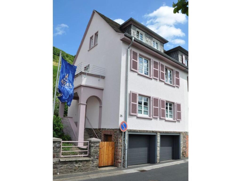 a white house with red shutters and a flag at Haus Rosa Comfortable holiday residence in Cochem