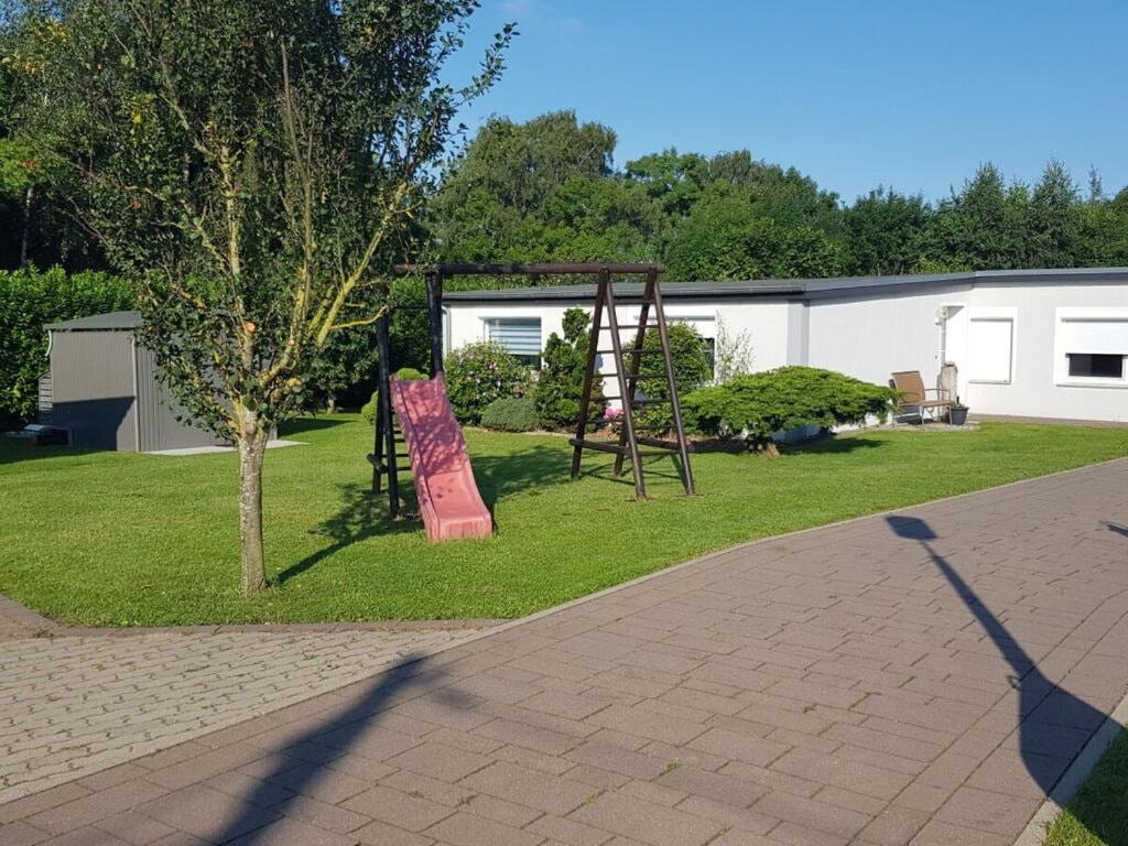un parque infantil en un patio con un árbol en Lighthouse view Modern retreat, en Bastorf