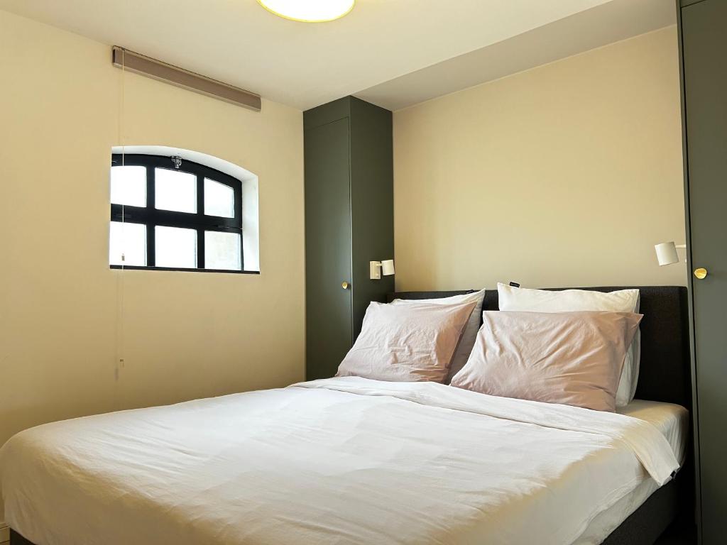 1 dormitorio con 1 cama con sábanas blancas y ventana en Sterrenbos, en Beers