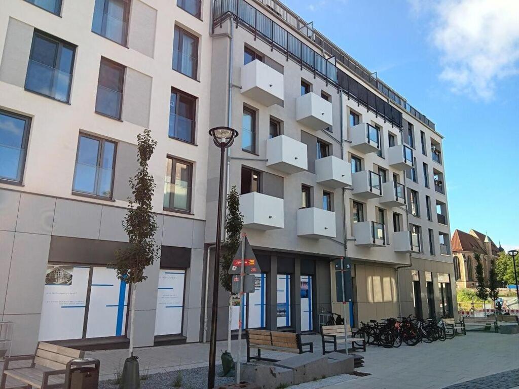 a large white building with benches in front of it at City center Modern retreat in Rostock