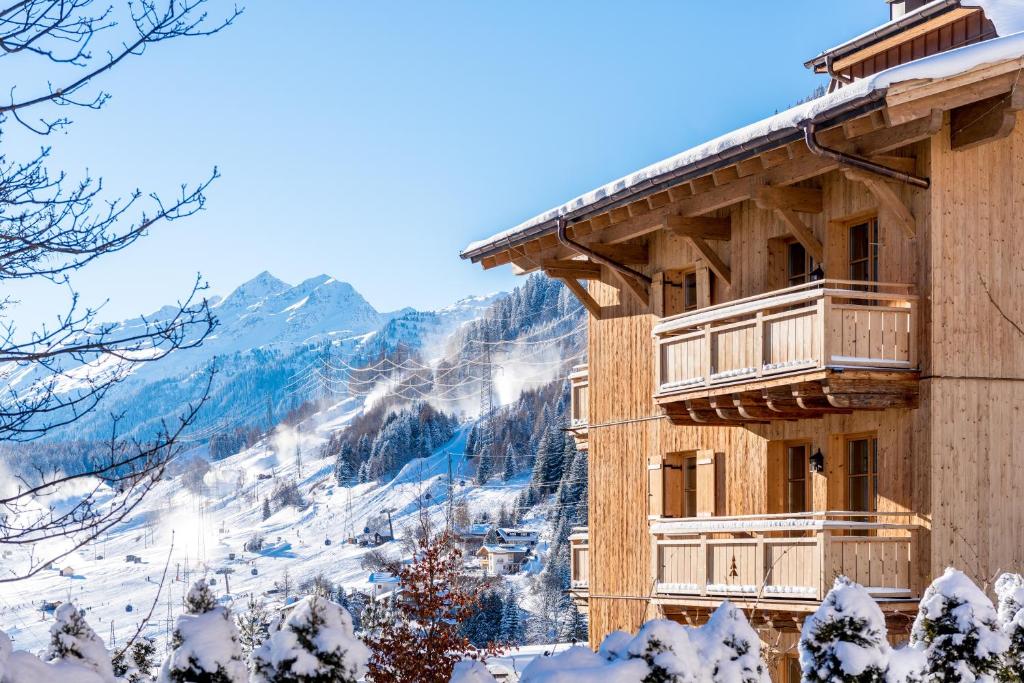 een gebouw met een met sneeuw bedekte berg op de achtergrond bij Hotel Tannenhof*****Superior in Sankt Anton am Arlberg