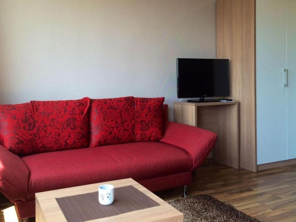 un sofá rojo en la sala de estar con TV en Saaleland Apartment 2, en Schleiz