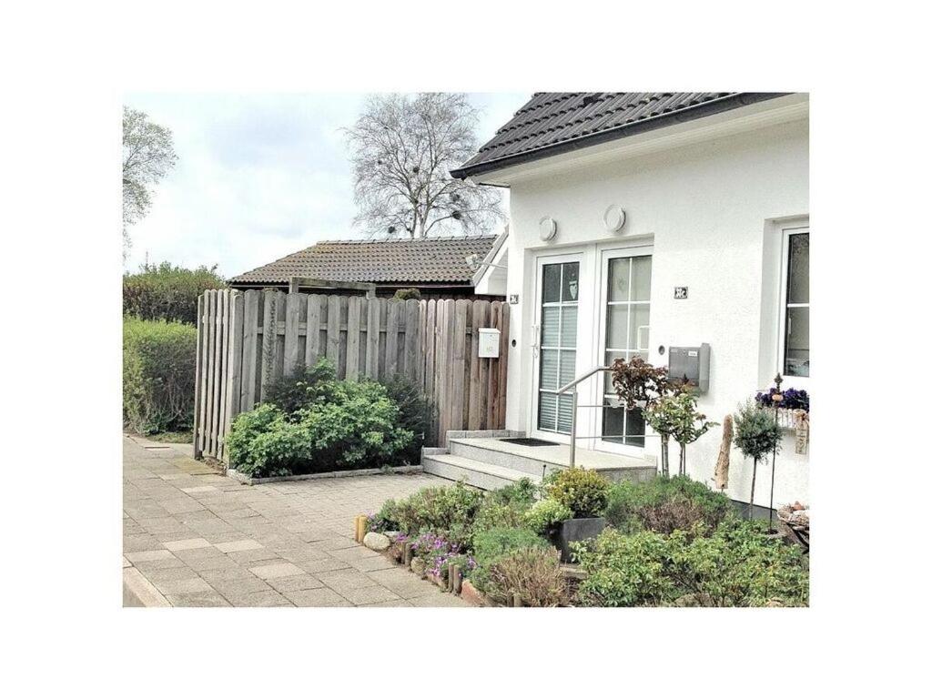 uma casa branca com uma cerca e um jardim em Maisonnette with charm em Scharbeutz