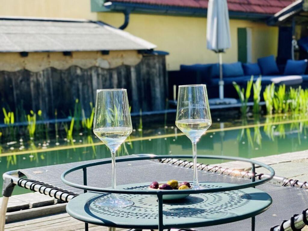 ZankenhausenにあるCozy Cottage Modern Retreatのプールサイドのテーブルに置かれたワイングラス2杯とフルーツプレート