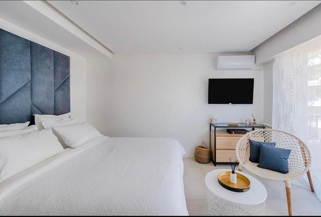 - une chambre blanche avec un lit, une chaise et une télévision dans l'établissement B045-Studio croisette AC close Congress center SEA, à Cannes