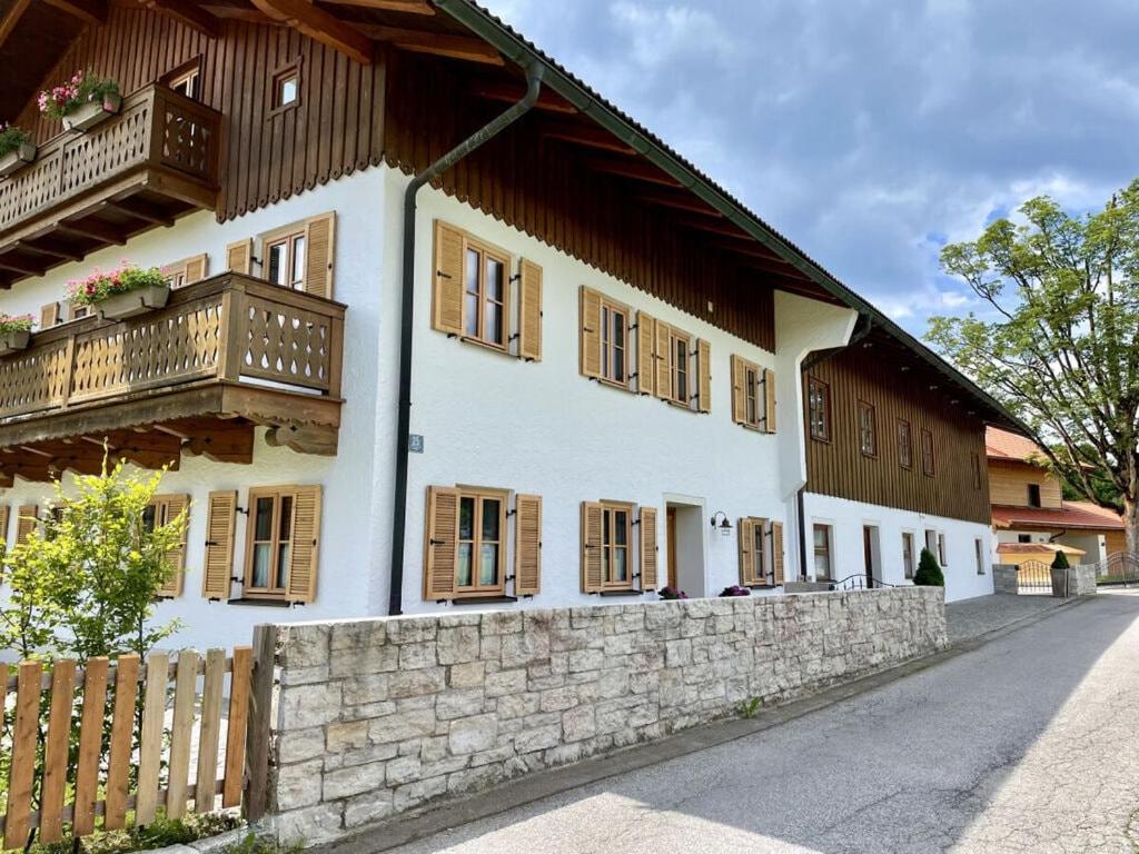 a white building with wooden windows and a stone wall at Oberland Stadlberg in Miesbach
