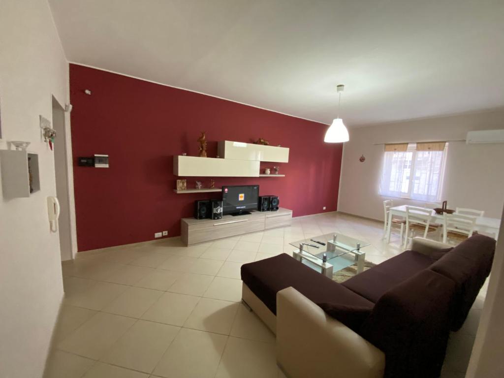 ein Wohnzimmer mit einem Sofa und einer roten Wand in der Unterkunft Appartamento Casa vacanza fronte mare in Venetico