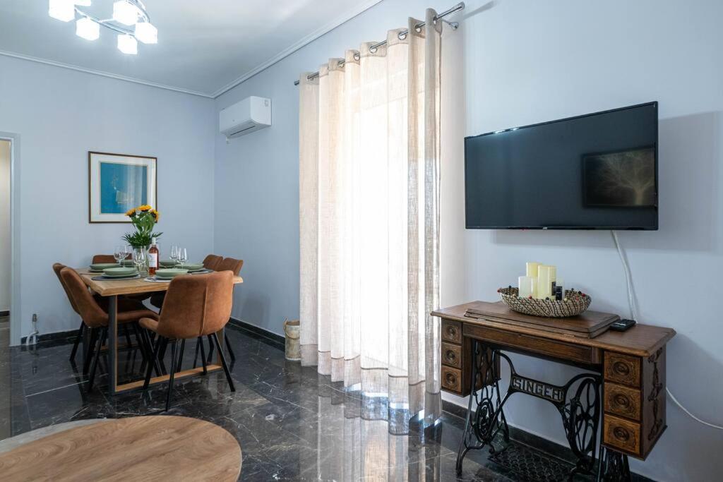 un soggiorno con tavolo e TV a parete di SkyVista Penthouse a Kalamáta