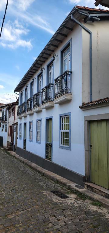 Pousada Laços de Minas في أورو بريتو: مبنى أبيض بشرفات على شارع