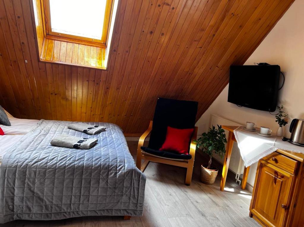 um quarto com uma cama, uma televisão e uma cadeira em Szyper 2 em Jastarnia