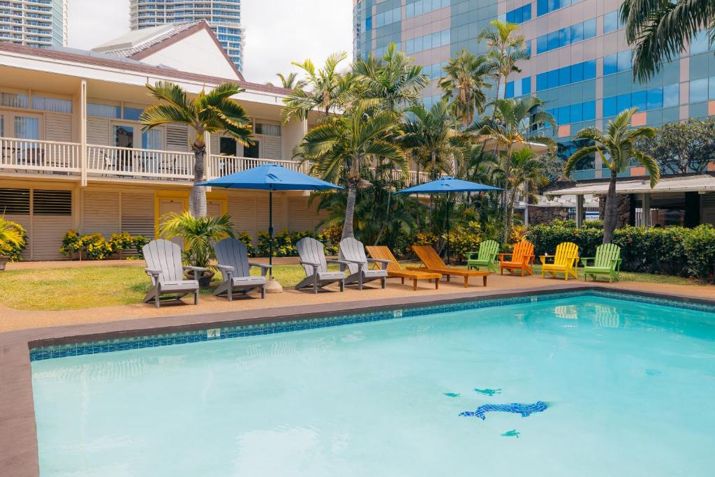 a pool at a hotel with chairs and umbrellas at Waikiki Heritage Hotel in Honolulu