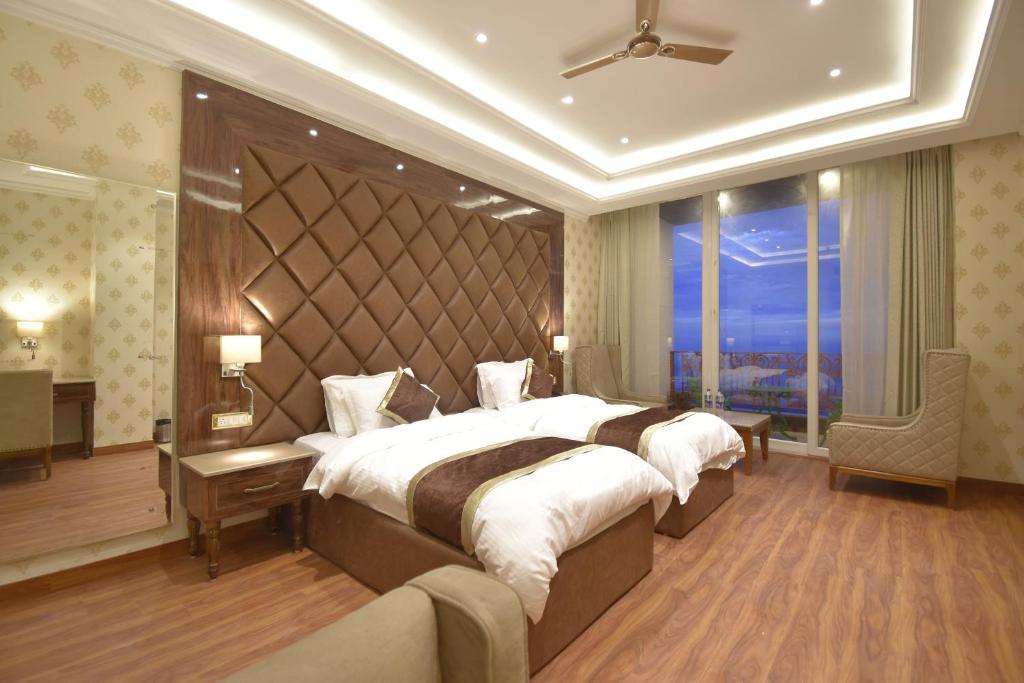 a hotel room with two beds and a large window at Grand Him Queen AC Centralized in Dharamshala