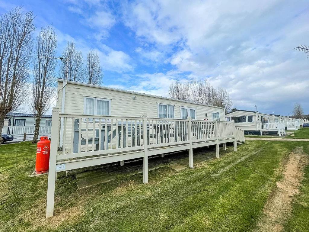 a house with a white deck and a red fire hydrant at Lovely Caravan With Decking At Manor Park In Hunstanton Ref 23091t in Hunstanton