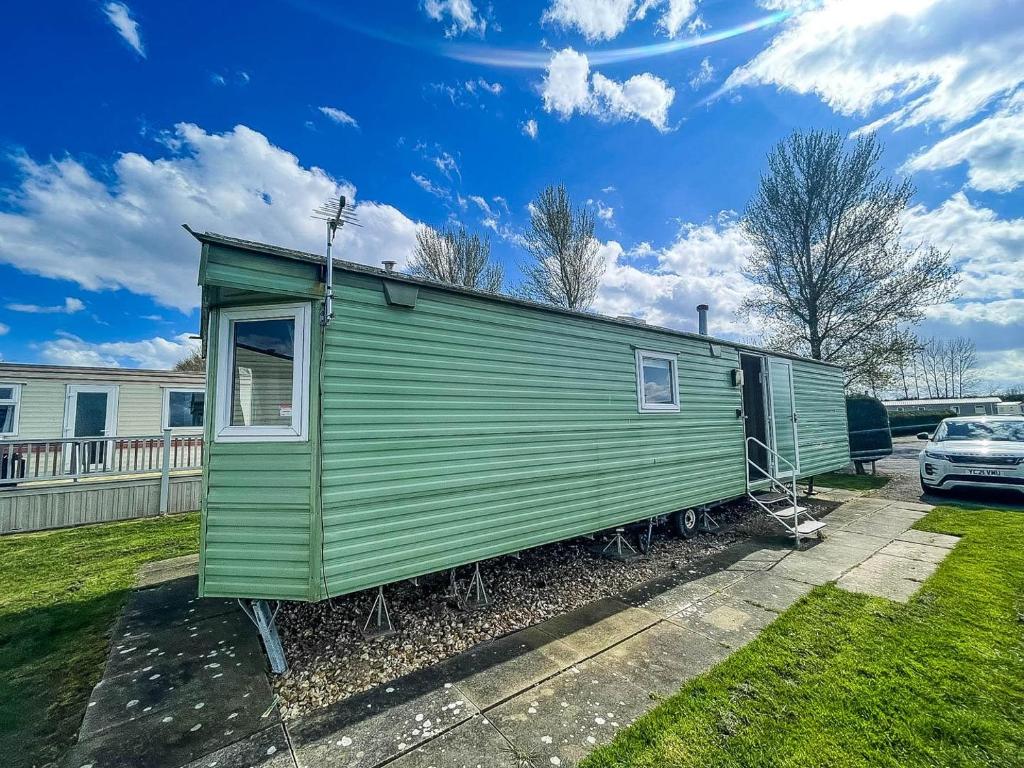 a green tiny house in a yard with a car at Lovely 8 Berth Caravan At Southview Holiday Park In Skegness Ref 33061c in Skegness