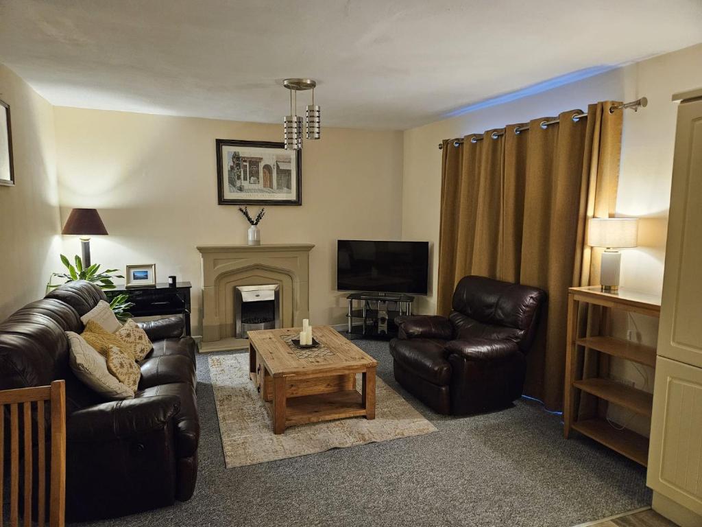 a living room with leather furniture and a fireplace at Main Street Swinford! in Swinford