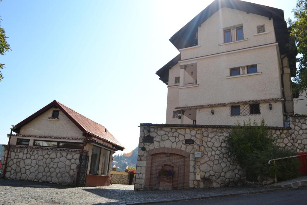 a large building with a stone wall next to a house at Pensiunea Casa Cranta in Braşov