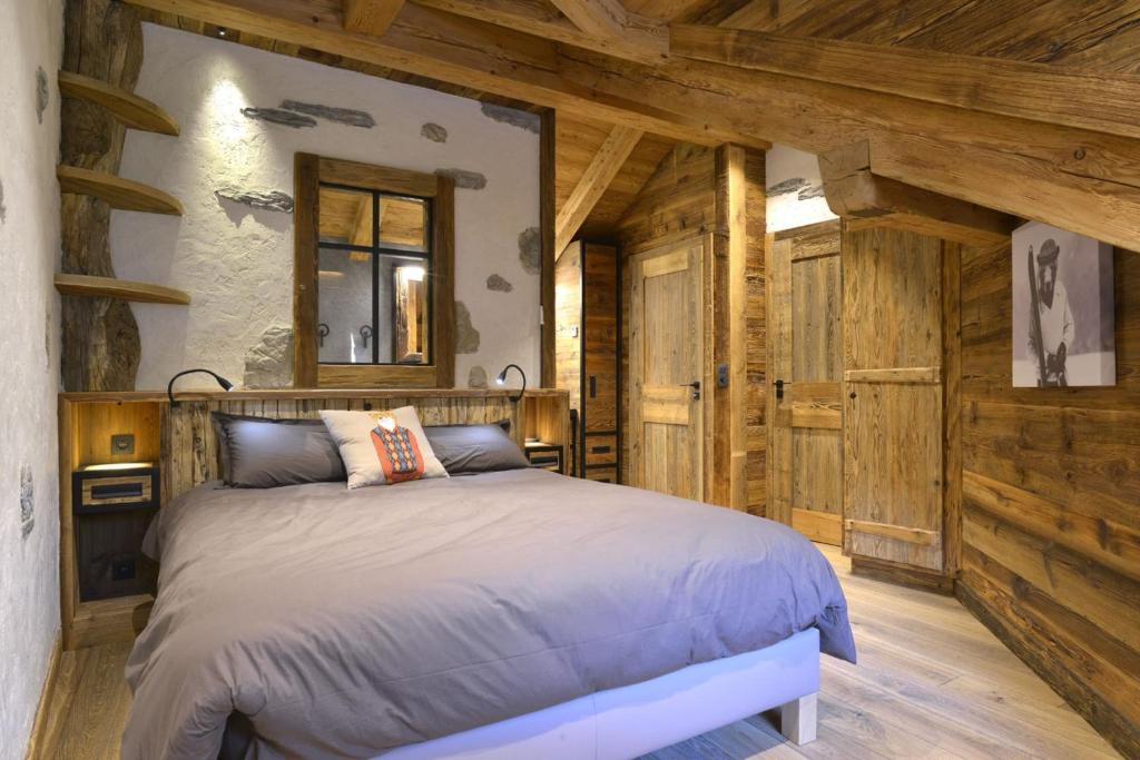 a bedroom with a bed in a room with wooden walls at La cabane luxury apartment in the heart of the village in La Grave